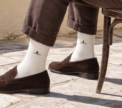AI concept crop showing white ribbed socks between brown trouser hems and brown suede loafers